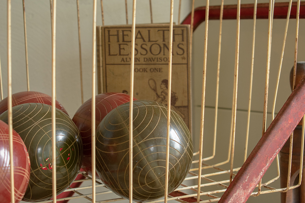 Antique miniature bowling balls in crate with health lessons book. Product photography for Relic Vintage.