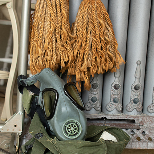 Green gas mask sitting in antique fabric. Product photography for Relic Vintage.