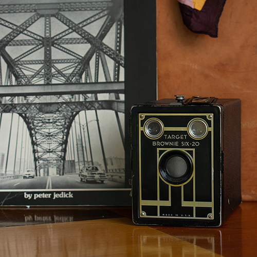 Antique camera on shelf with vintage book. Product photography for Relic Vintage.