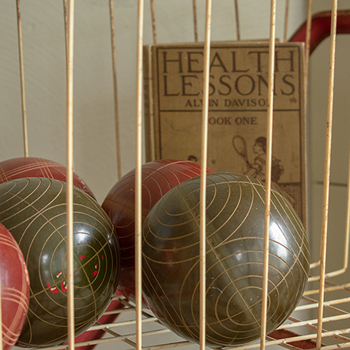 Antique miniature bowling balls in crate with health lessons book. Product photography for Relic Vintage.